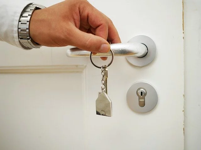man holding house keys in front of a door handle